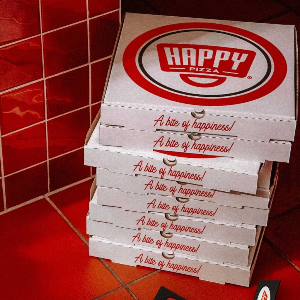 A creative agency develops Happy Pizza branded materials, ensuring every piece radiates the joy of pizza sharing.